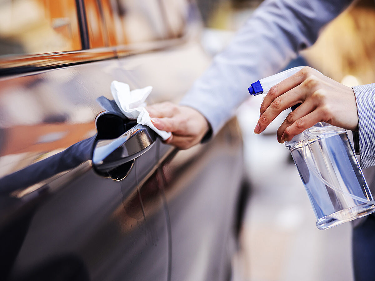 Closeup of woman disinfecting door lock on her car to prevent spreading corona virus.