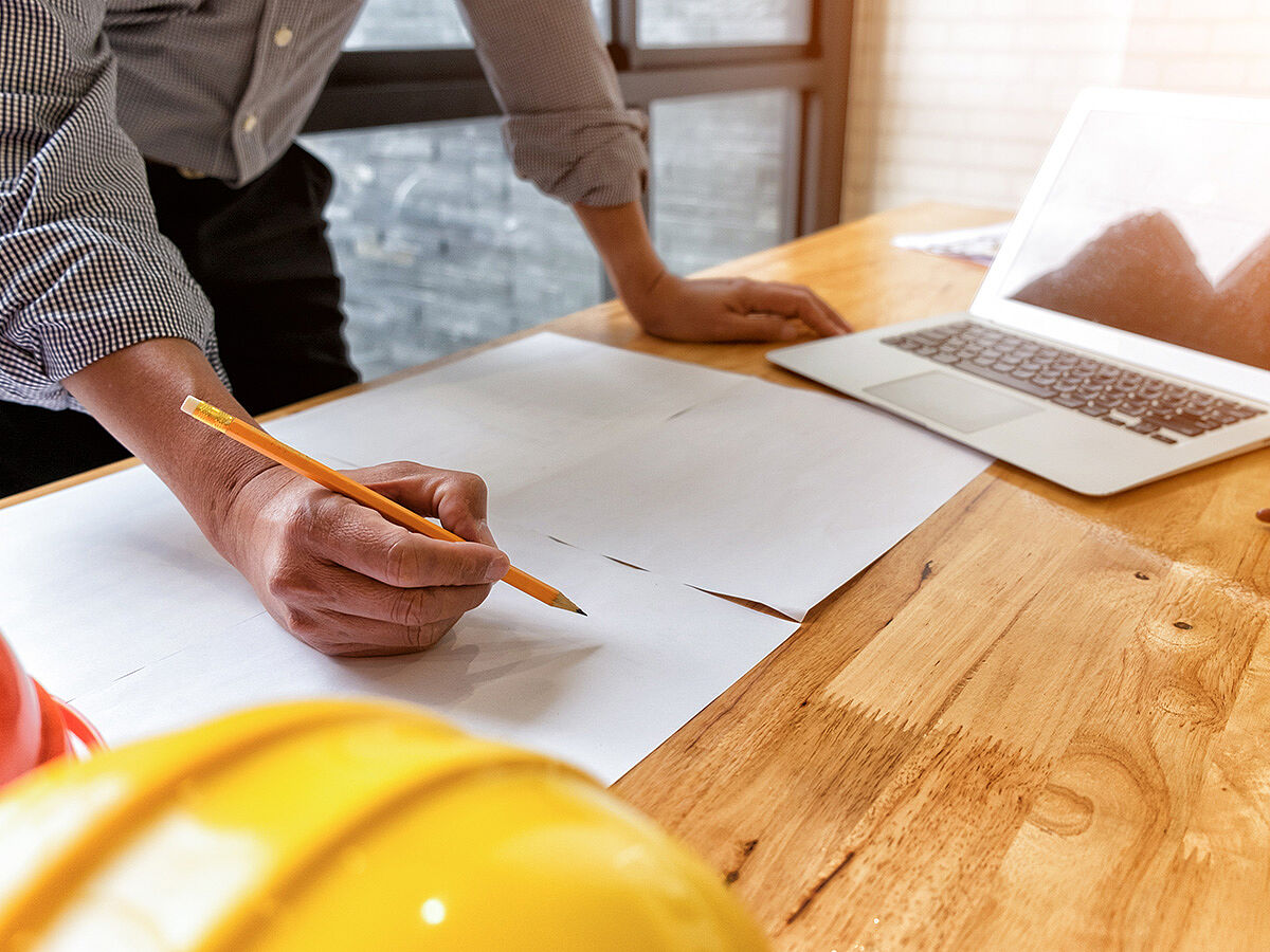 architect drawing architectural project on blueprint with laptop, engineering concept, architecture concept, soft focus, vintage tone